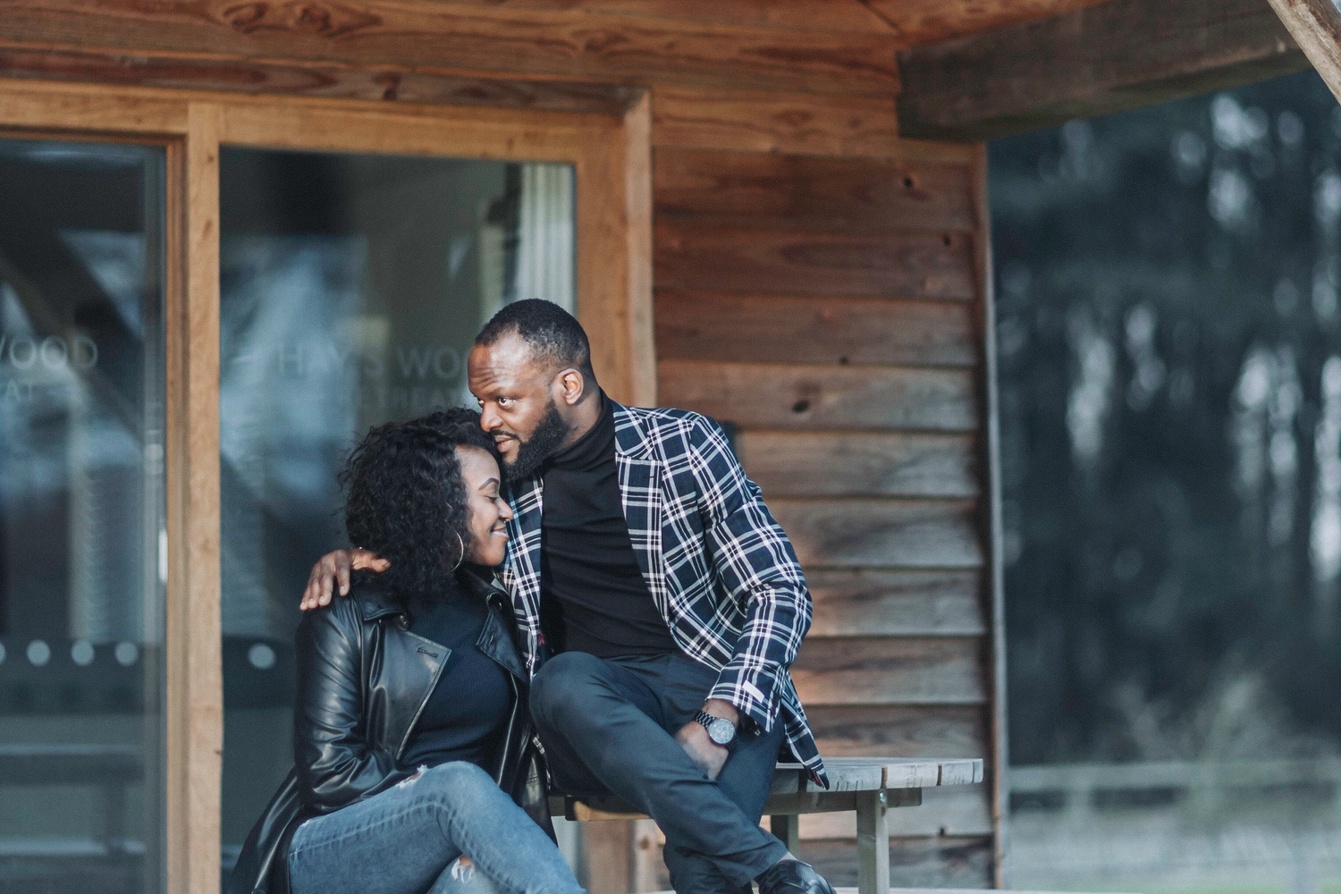 Couple sitting outside their luxury lodge at Hay’s Wood Retreat in Norfolk, enjoying a peaceful nature escape. Ideal for romantic getaways and relaxing countryside holidays.