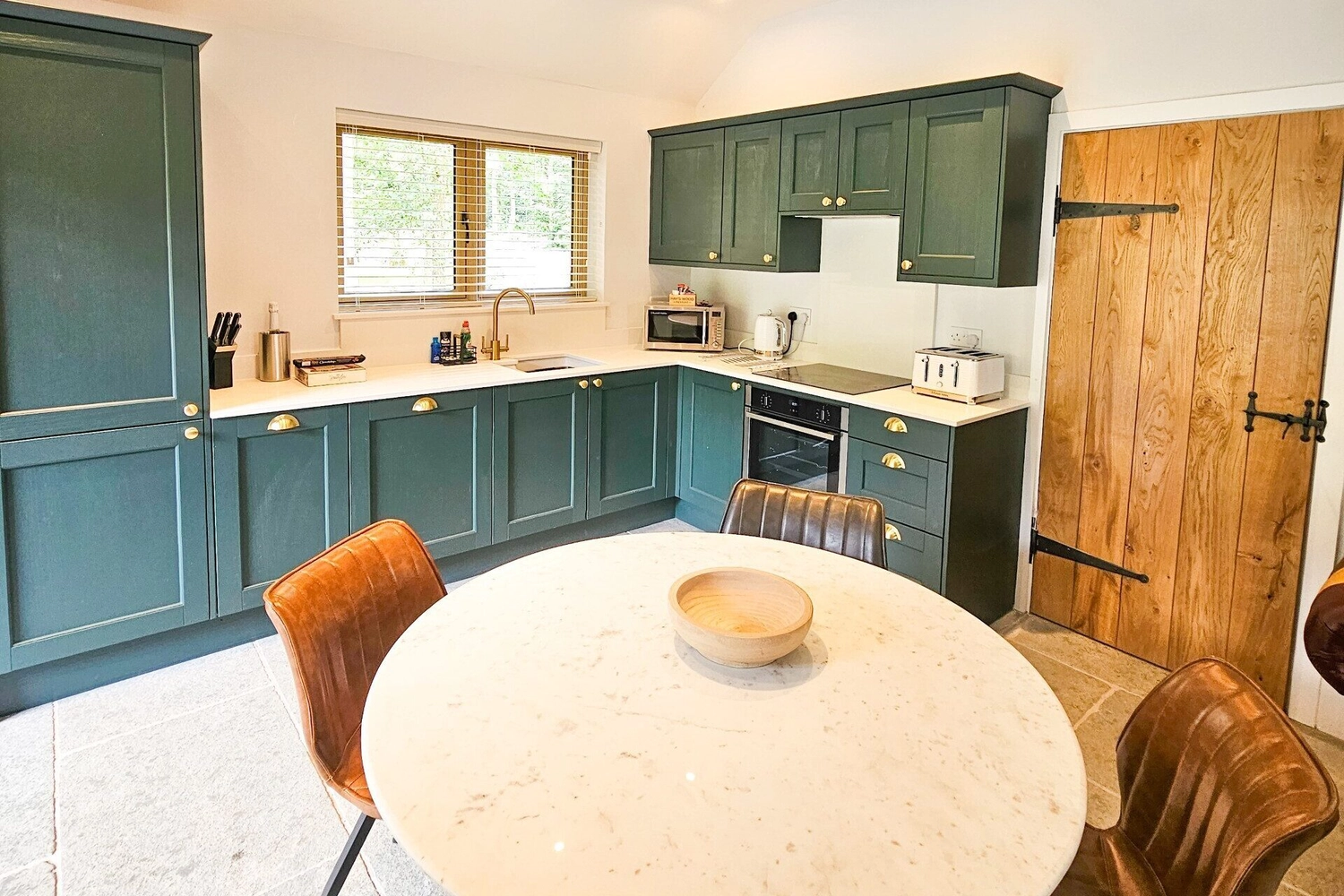 Bright and modern kitchen and dining area inside a hot tub lodge at Hay’s Wood Retreat in Norfolk, UK. The open-plan space features sleek appliances, ample counter space, and a wooden dining table with seating for guests to enjoy self-catering meals. This well-equipped lodge offers a comfortable base for countryside breaks with family or friends, complemented by private hot tub access and peaceful woodland surroundings.