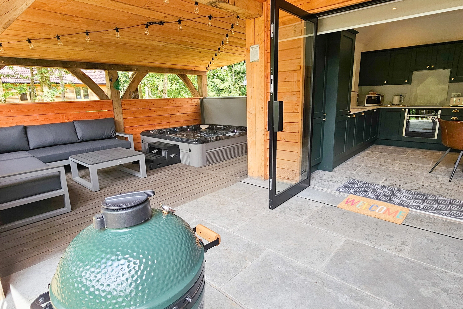 Luxurious private patio of our hot tub lodge at Hays Wood Retreat, featuring a relaxing hot tub, convenient Green Egg BBQ, and easy access from the ground floor, perfect for enjoying your Norfolk getaway.