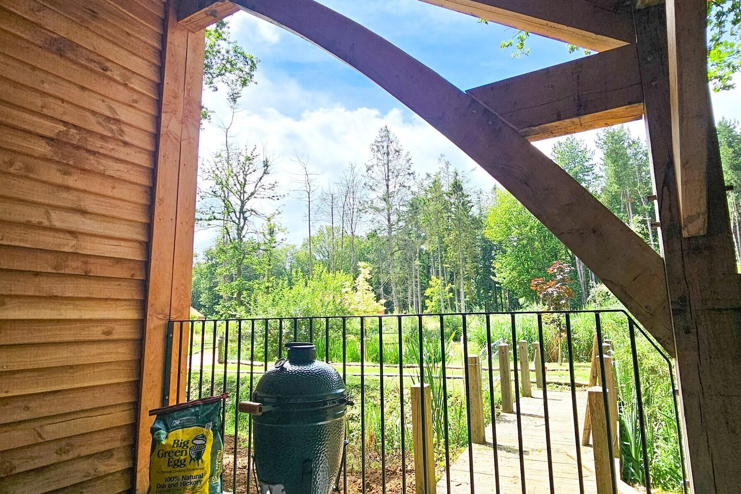 Outdoor green-egg barbecue grill set up at our hot tub lodge with the lush woodland of Hay’s Wood Retreat in Norfolk, UK, visible in the background. Perfect for guests enjoying self-catering breaks, the BBQ area offers a great way to cook al fresco while surrounded by peaceful countryside and natural woodland, making it ideal for family gatherings and outdoor meals in a tranquil retreat setting.