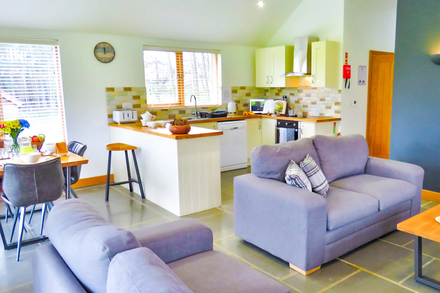 Spacious open-plan living area within our luxury lodge at Hays Wood Retreat, featuring comfortable seating and a modern kitchen in the background, ideal for socialising on your Norfolk holiday.
